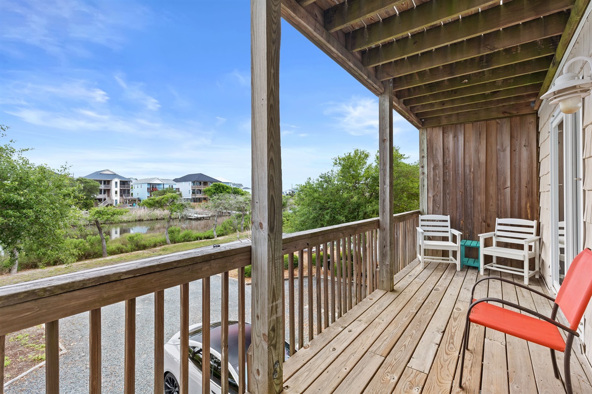 Covered porch seating with relaxing neighborhood and waterway views