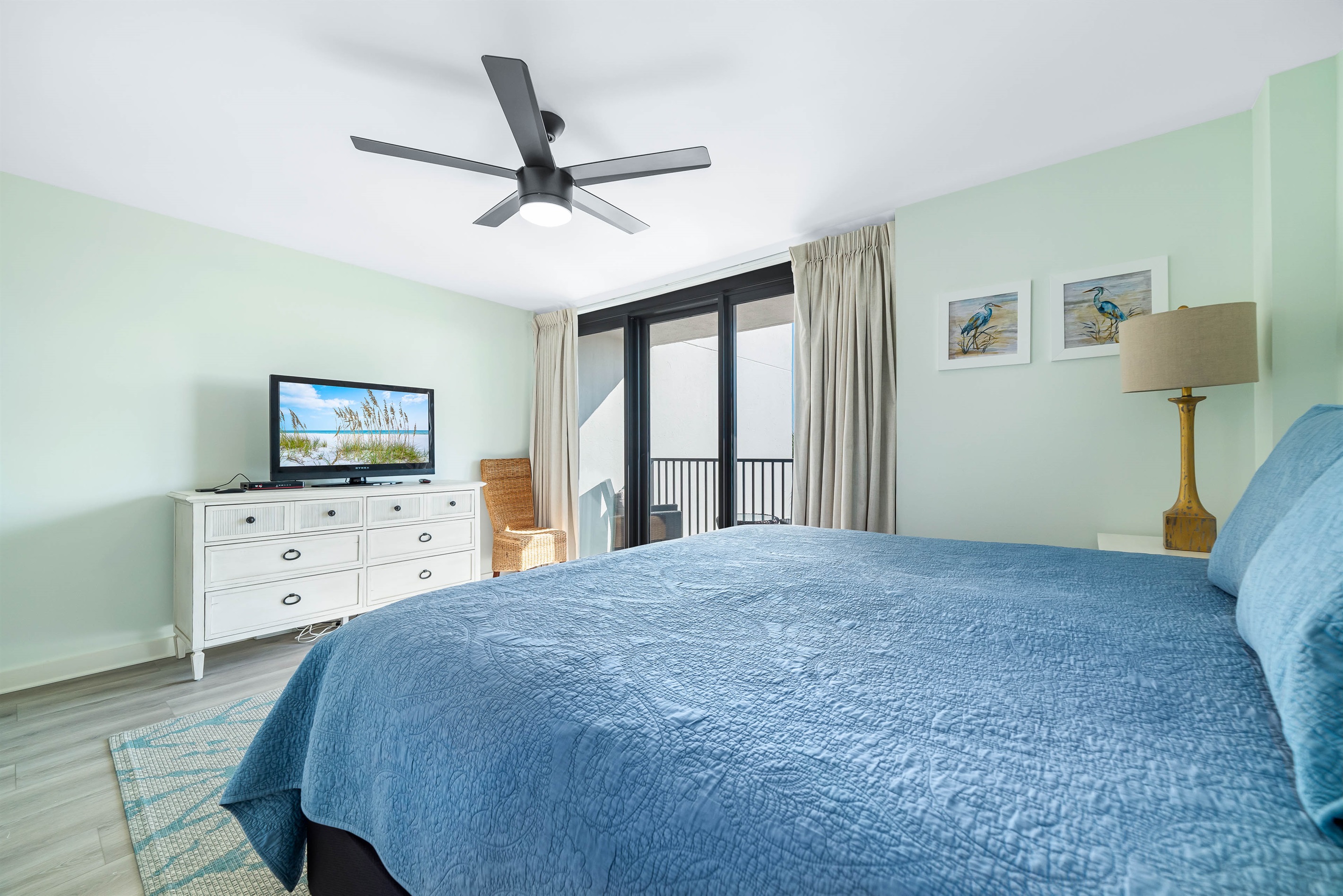 This spacious primary bedroom offers a comfortable king-size bed and a private balcony overlooking the tennis court and Orange beach across the street.