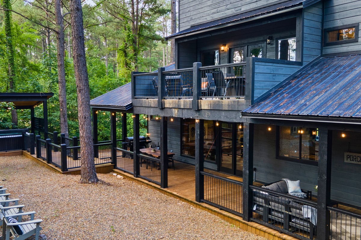 Side view of a contemporary cabin with multiple decks and a screened porch nestled in the woods.