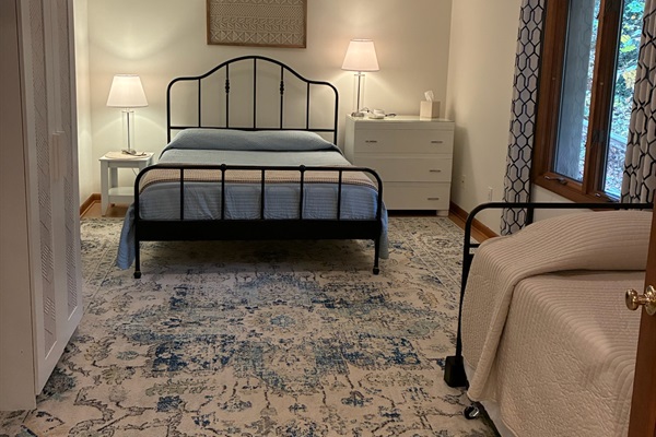 Bedroom has a queen bed, dresser, free-standing closet and trundle bed.