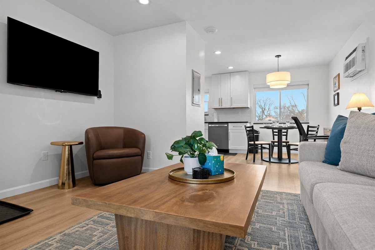 Spacious open-concept living area with cozy seating, smart TV, and seamless flow into the kitchen and dining space—perfect for relaxing or entertaining.