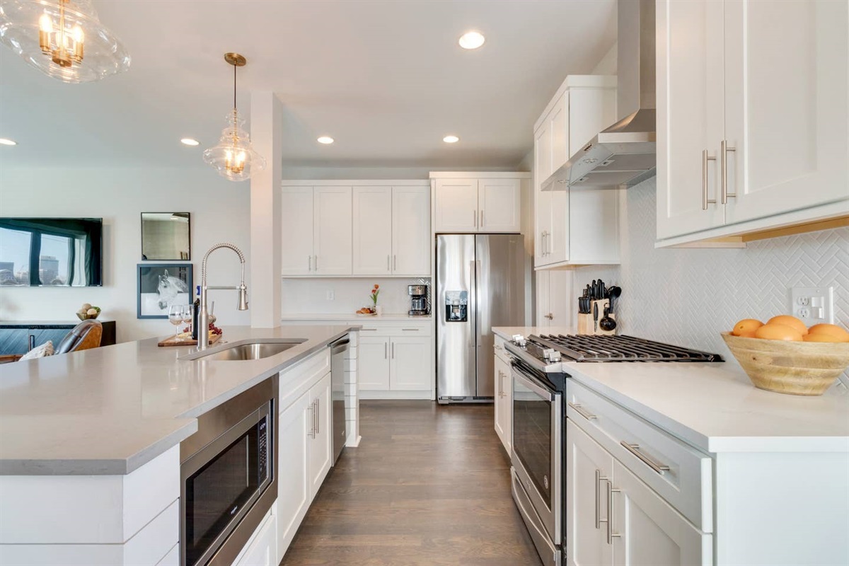 - Fully stocked kitchen with stainless steel appliances, gas stove, & center island - White shaker cabinets, quartz countertops, & herringbone backsplash elevate the design - Perfect for preparing group meals, morning coffee, or gathering at the bar stools