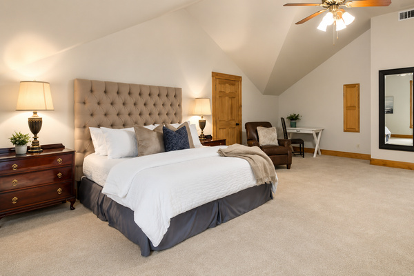 Unwind in this spacious bedroom featuring a plush king bed, soaring ceilings, a cozy sitting area, and a dedicated workspace—plenty of room to relax and recharge after a day on Lake Travis.