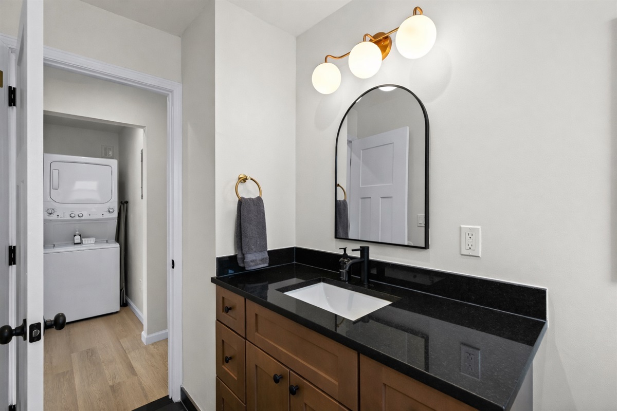 Fresh, modern bathroom with a sleek vanity, warm lighting, and thoughtful touches—conveniently located near the in-unit laundry for added ease.