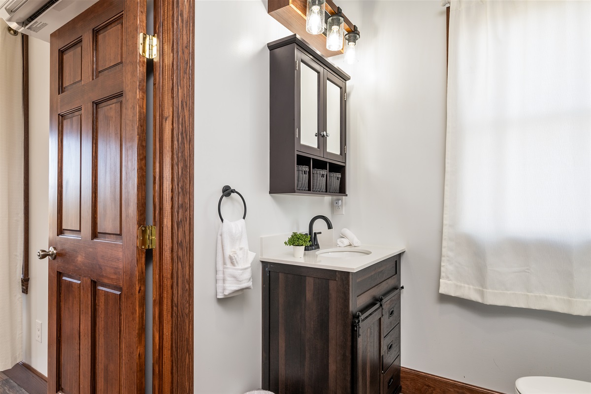 Stylish bathroom with dark vanity, bright lighting, and modern fixtures.