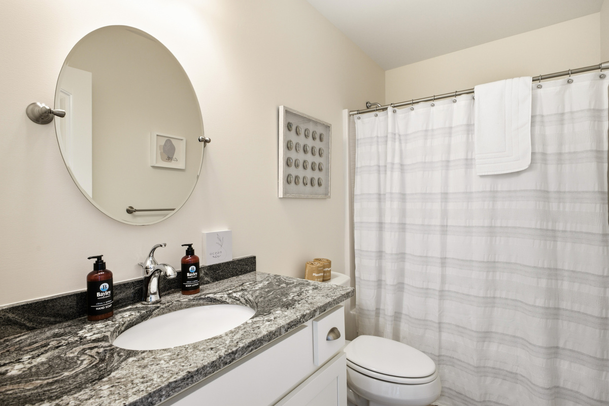 Clean, well-appointed full bathroom with a spacious vanity, large mirror, toilet, and shower/tub combination with fresh towels provided.