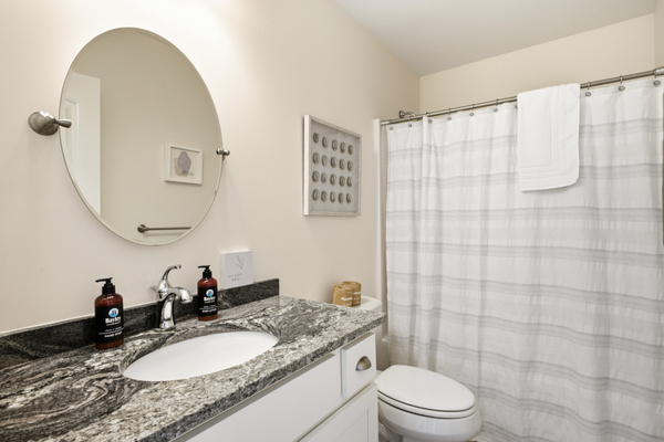 Clean, well-appointed full bathroom with a spacious vanity, large mirror, toilet, and shower/tub combination with fresh towels provided.