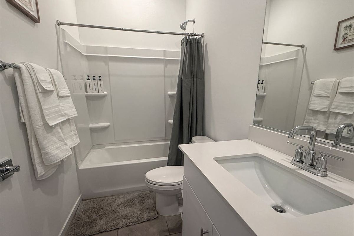 Bathroom with tub-shower, toilet, vanity, mirror, and towels