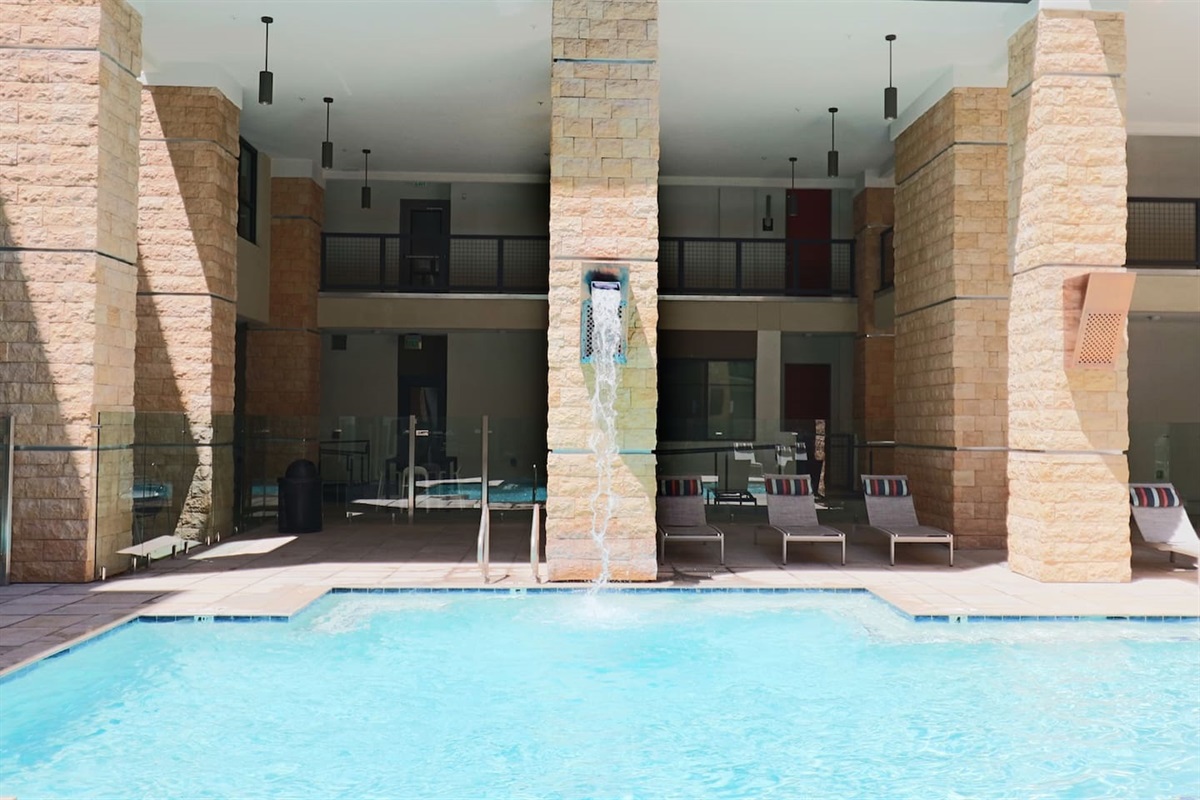 - Lounge by the pool beneath covered columns and refreshing water streams   - Relax in shaded comfort with modern lounge chairs and serene surroundings   - Ideal for cooling off, reading, or sunbathing in peaceful outdoor bliss