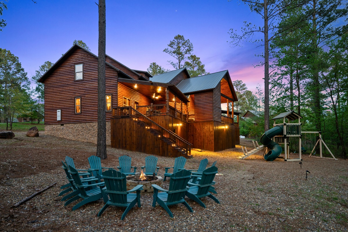 A warm welcome awaits as you pull up to the cabin, where glowing lights and a peaceful wooded setting set the tone for a relaxing stay.