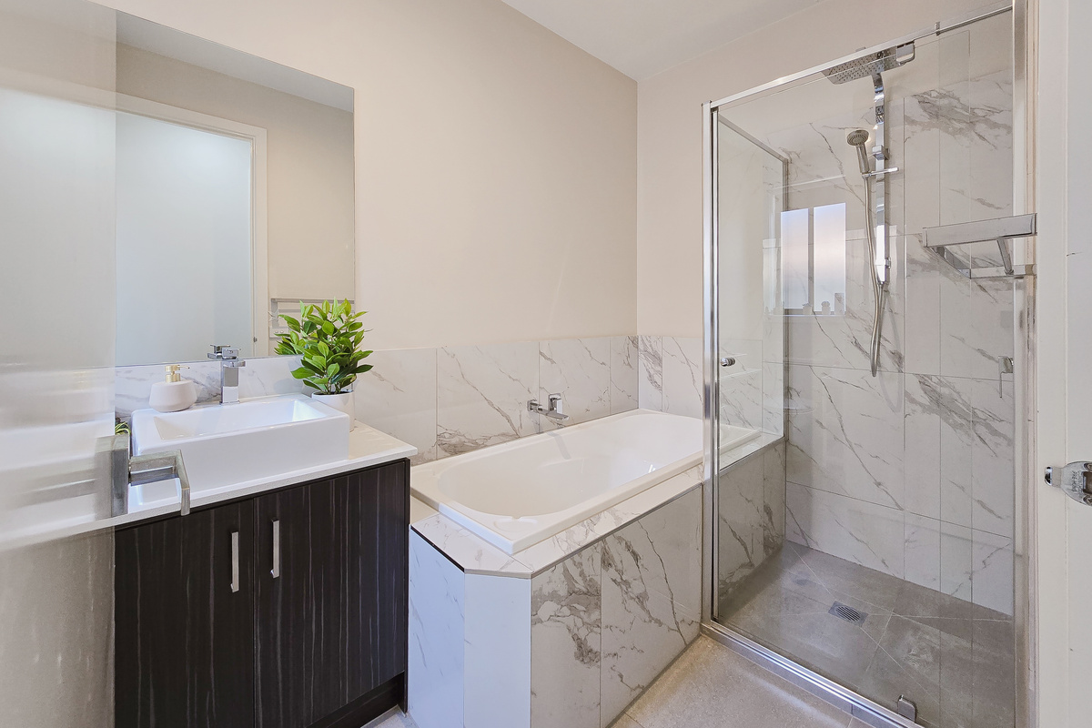 Main bathroom with bathtub, separate glass shower, vanity and large mirror.