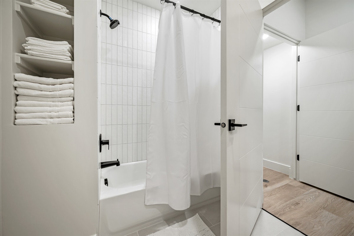 Stocked with plush towels and a clean, modern tub-shower combo, this bathroom is ready for your stay.
