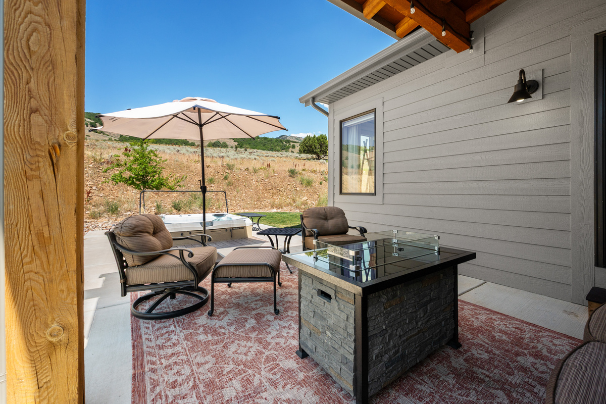 Enjoy mountain breezes from the covered patio featuring cushioned seating, a fire table, and easy access to the private hot tub.