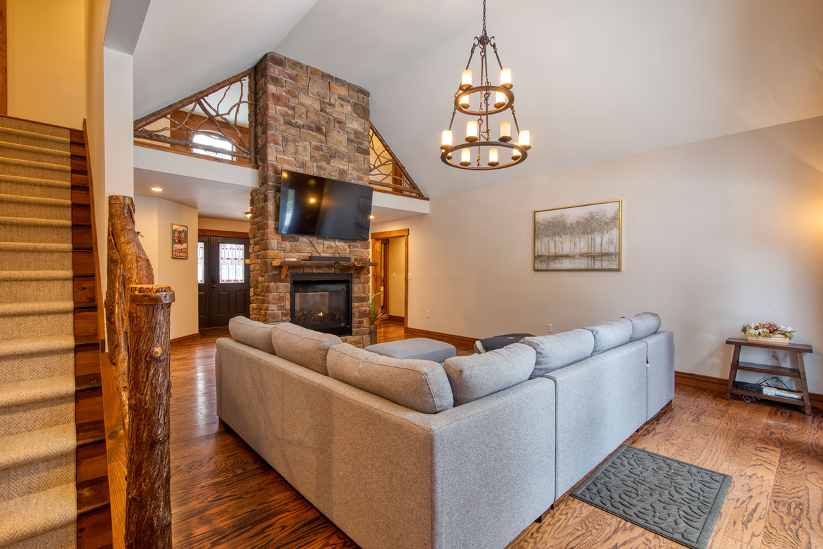 The open-concept great room features soaring ceilings, a stunning stone fireplace, and comfortable seating for everyone.