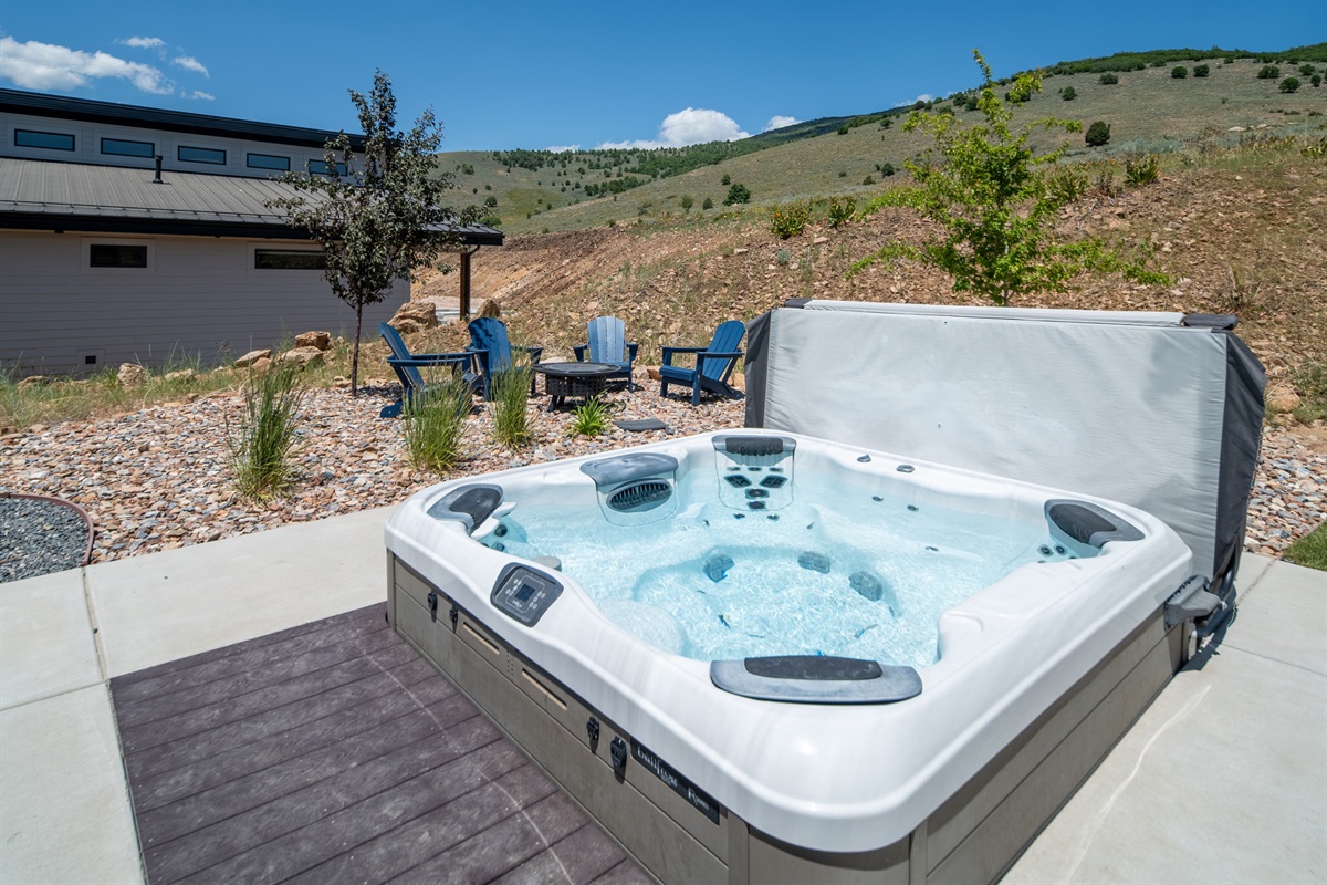 Private hot tub with nearby fire pit seating and hillside views