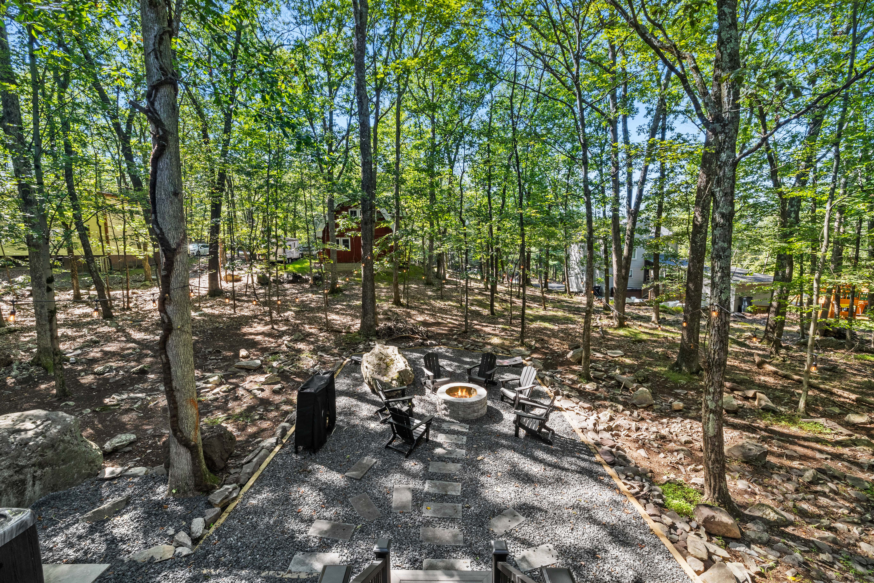 A dedicated stone circle with Adirondack chairs surrounded by mature forest trees.