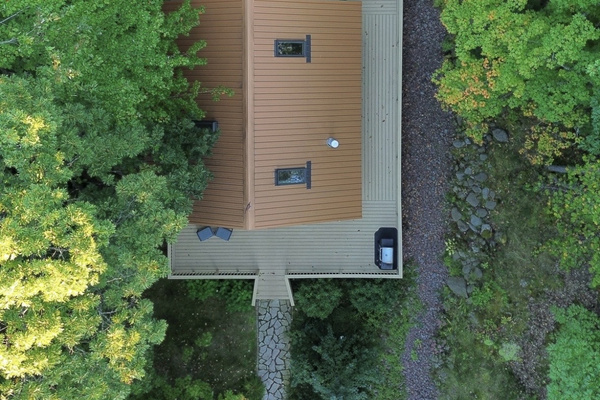 Main Cottage ariel view 1k wrap around deck , grill, seating chairs in front , lounge couch and table in back deck with propane fireplace. 