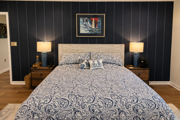 Main-floor primary bedroom with a king bed, cozy lighting and a calm, comfortable layout.
