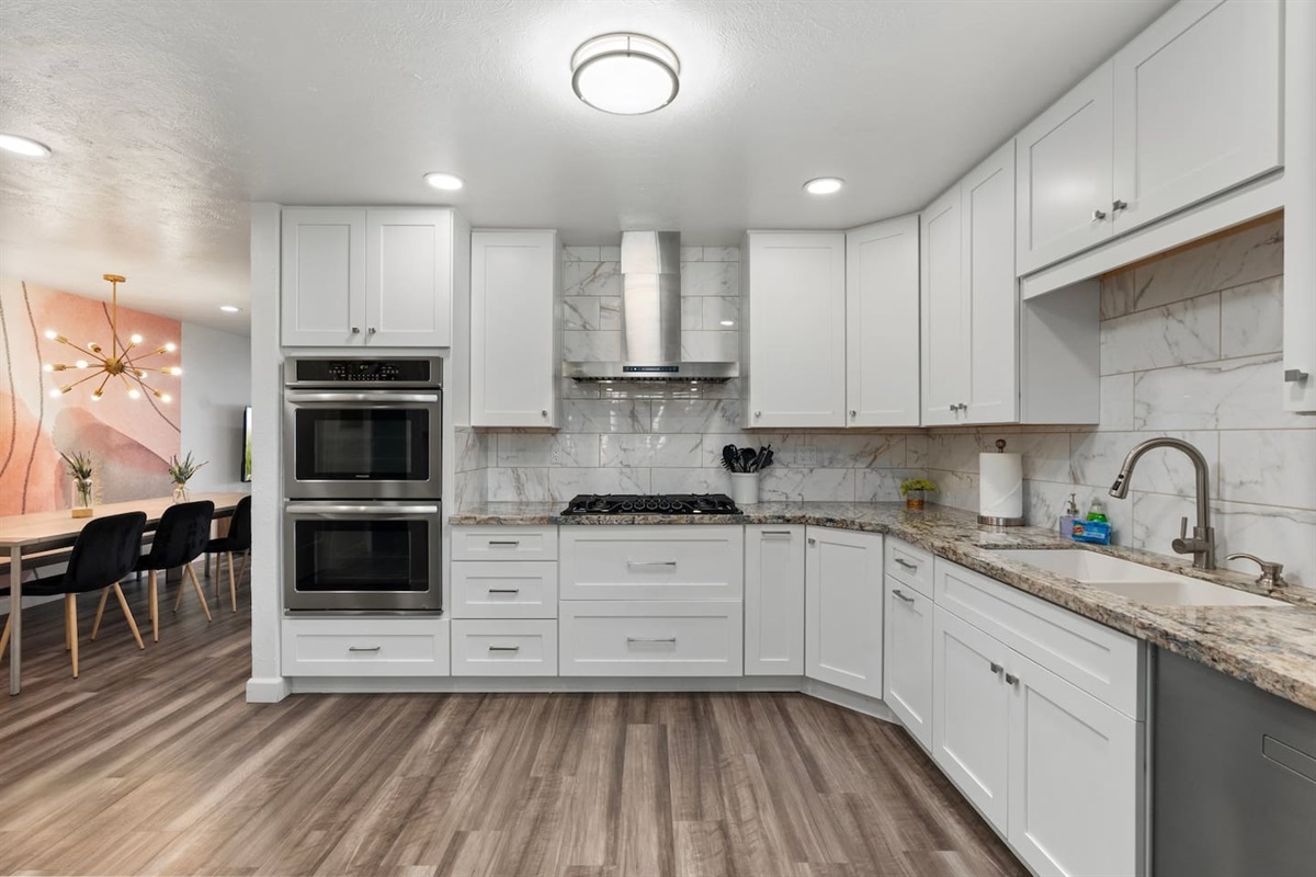 Crisp white cabinetry, marble backsplash, and stylish lighting make this kitchen both functional and beautiful.

