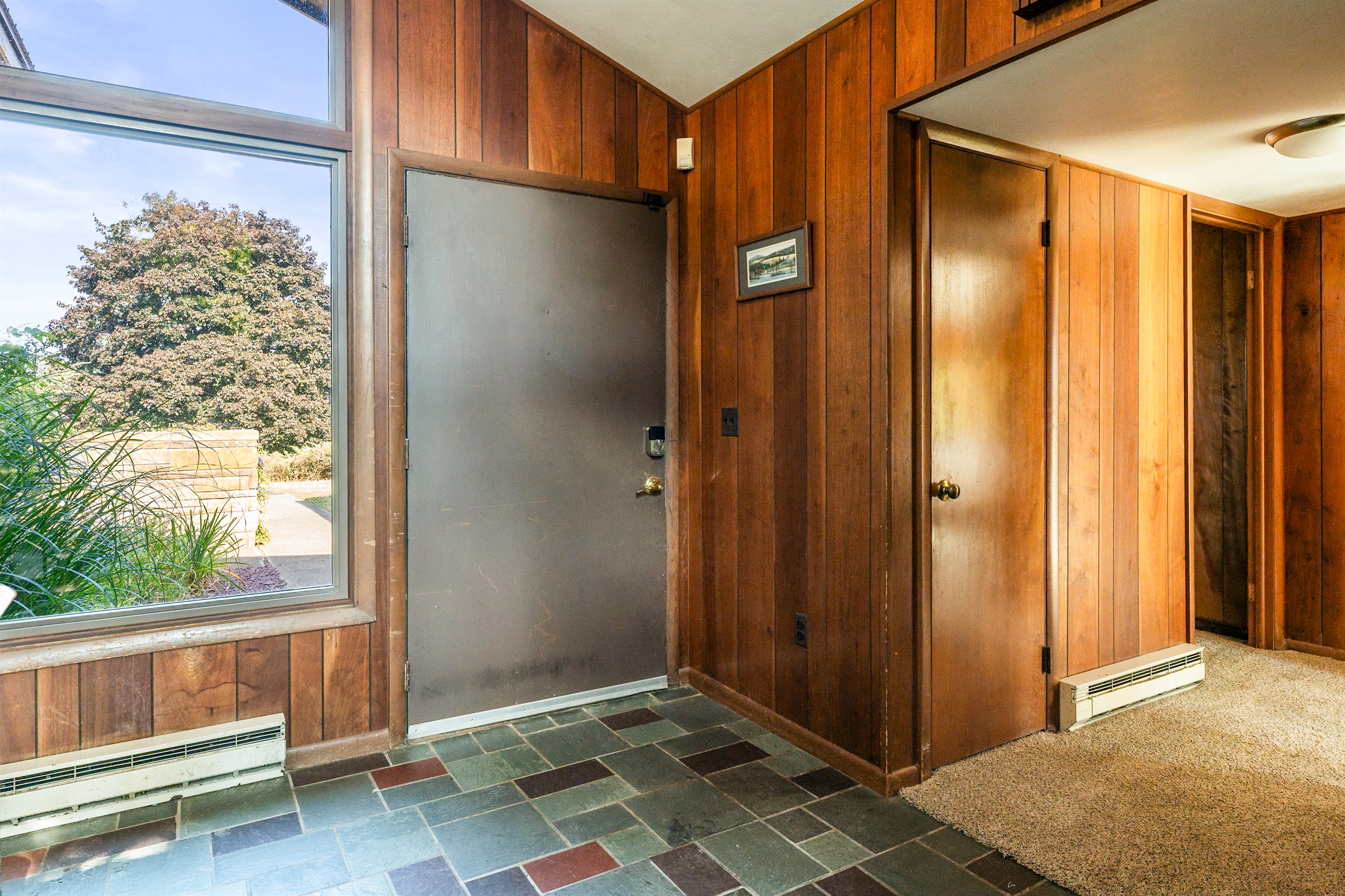 Warm wood-paneled entryway with stone flooring, blending rustic character and timeless charm.