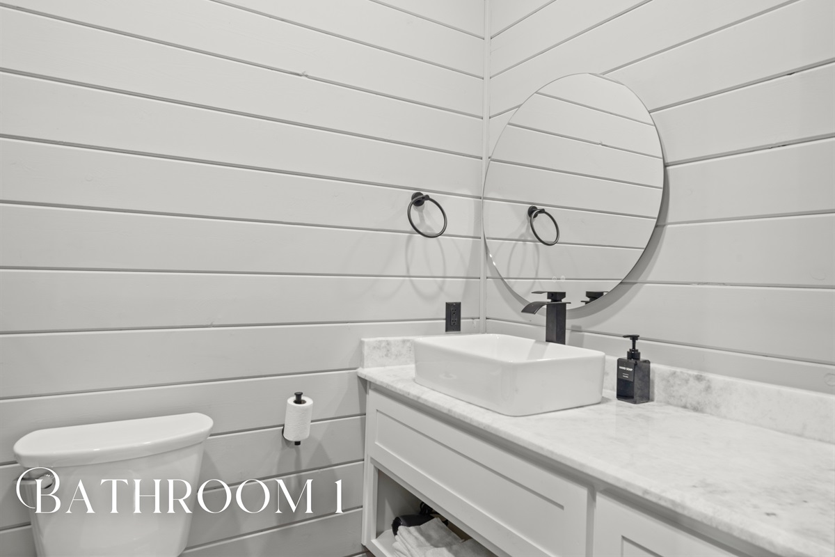 The first bathroom features double sinks, bright shiplap walls, and timeless style—perfect for getting ready together without feeling crowded.
