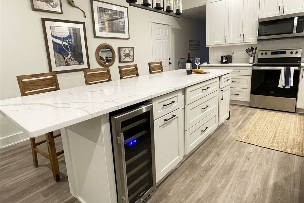 Beautifully appointed kitchen featuring quartz countertops, large center island, bar seating, and stainless steel appliances.