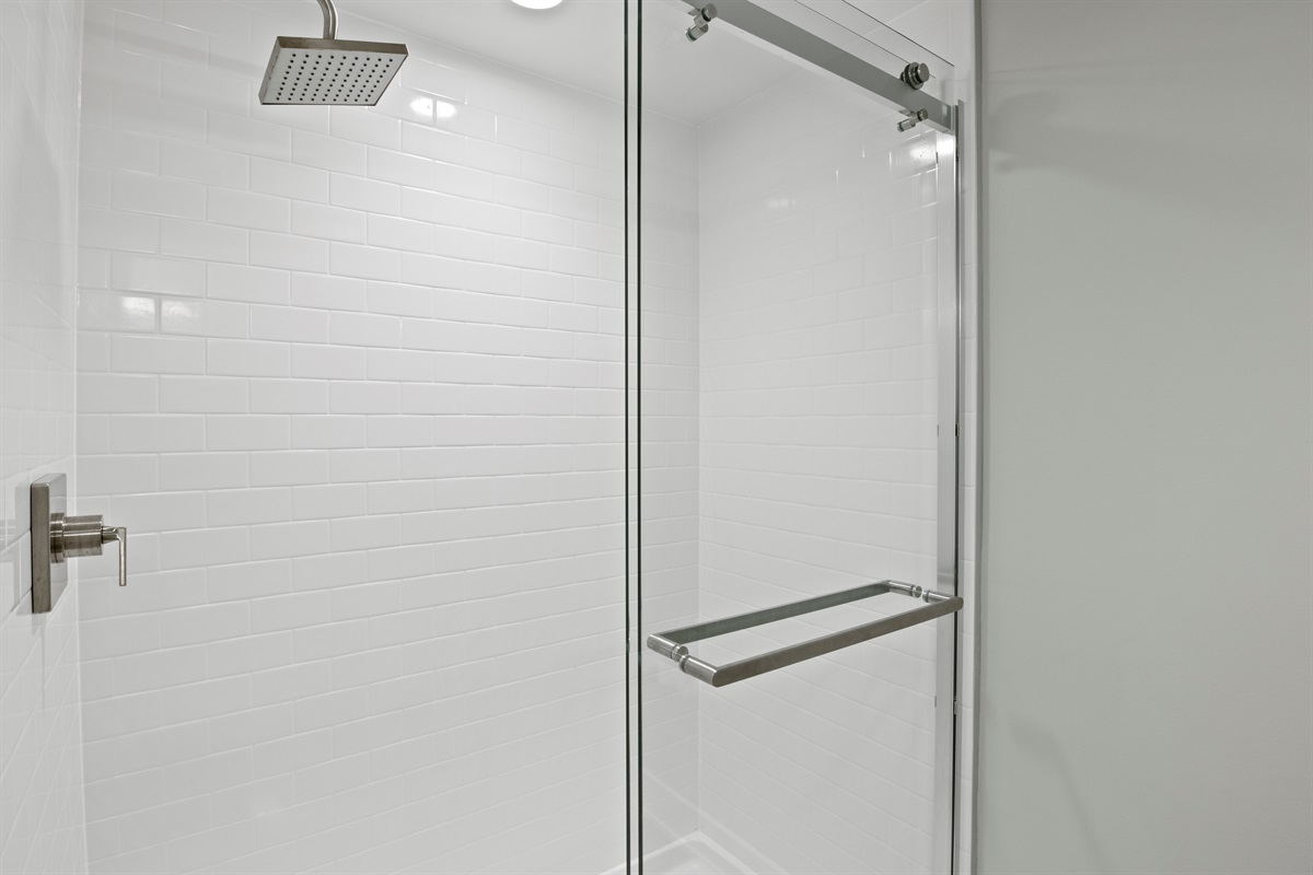 Crisp, clean walk-in shower with subway tile and rainfall showerhead — a refreshing escape after a day of adventure.