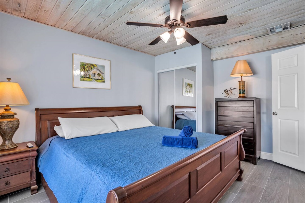 Bedroom 2 Jr. suite with King sized bed, sliding door exit to pool, wide door entrance, ceiling fan, dresser, closet and smart tv. 