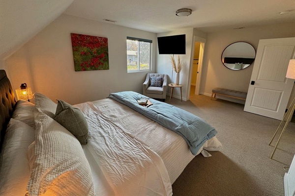 This primary bedroom features a king bed, black out shades, television, and a generous walk-in closet space. 