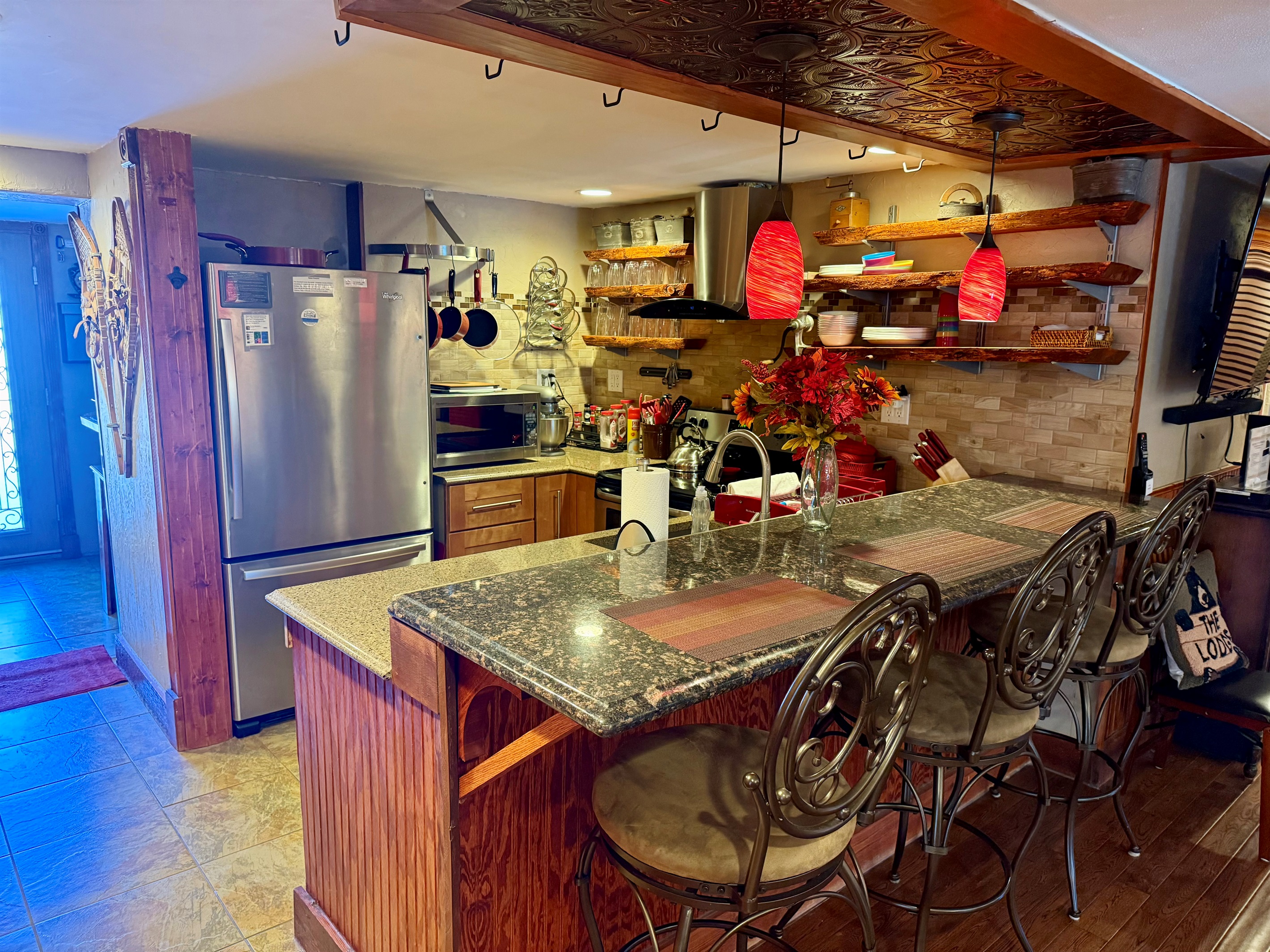 Fully equipped kitchen with bar seating, open shelving, and everything needed for cooking and gathering.