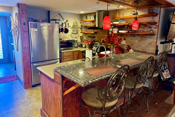 Fully equipped kitchen with bar seating, open shelving, and everything needed for cooking and gathering.