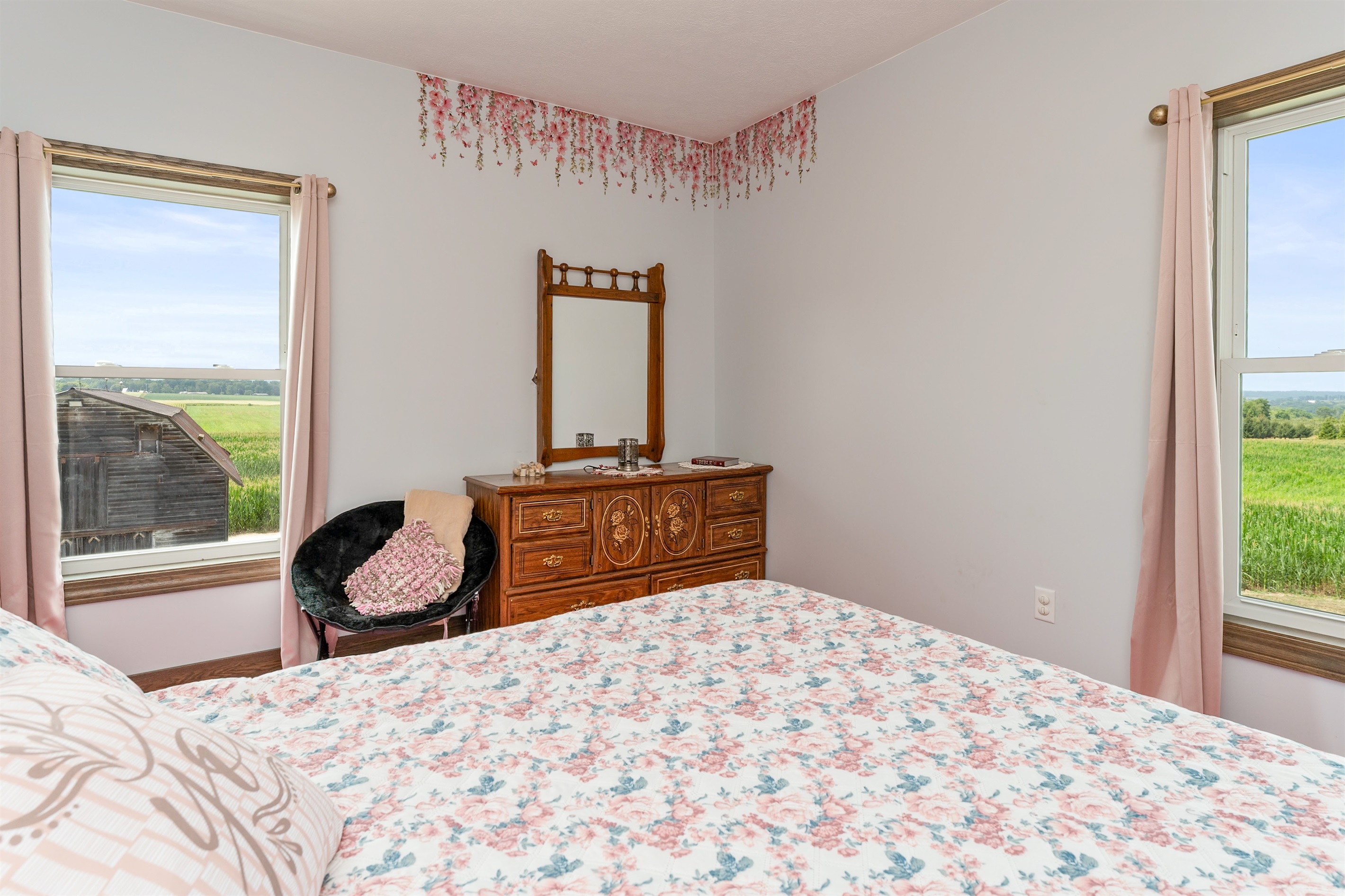 Peaceful Queen bedroom retreat with floral bedding, elegant wood furniture, and delicate wall art creating a warm, restful ambiance. Bedroom #2