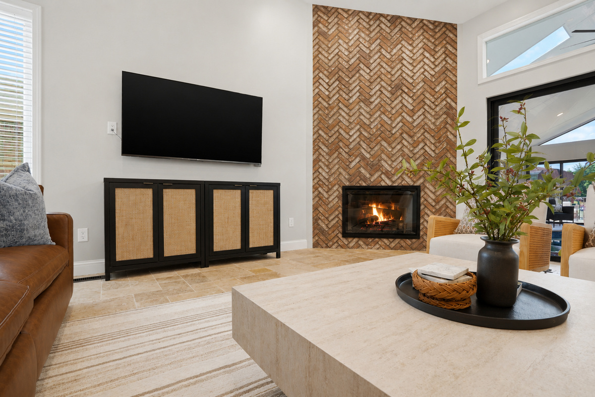 Modern open-concept living room with a sleek fireplace, textured accent wall, and large TV. Bright, stylish space with warm finishes and a cozy yet upscale atmosphere perfect for relaxing or entertaining.