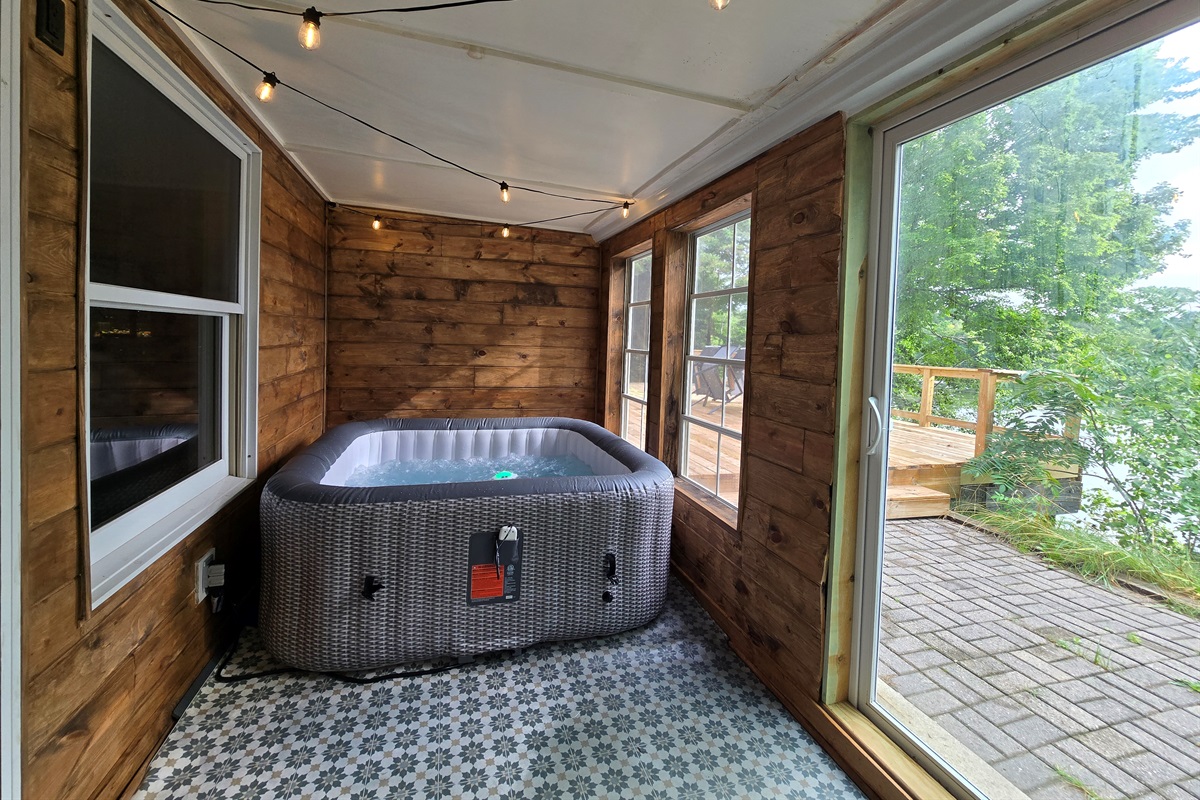 Relax in your private hot tub with lake views! 💦✨ Set in a cozy cedar sunroom with string lights and big windows, it’s the perfect spot to warm up after adventures or unwind under the stars.