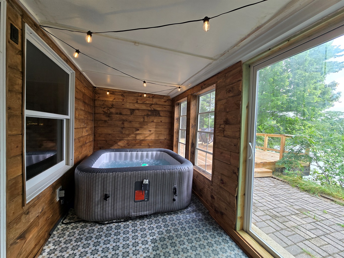 Relax in your private hot tub with lake views! 💦✨ Set in a cozy cedar sunroom with string lights and big windows, it’s the perfect spot to warm up after adventures or unwind under the stars.