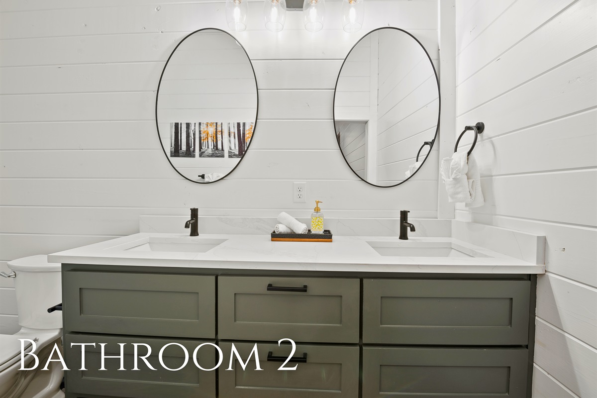 Modern bathroom showcasing dual sinks with rectangular mirrors over a green vanity, providing a sleek, clean design.