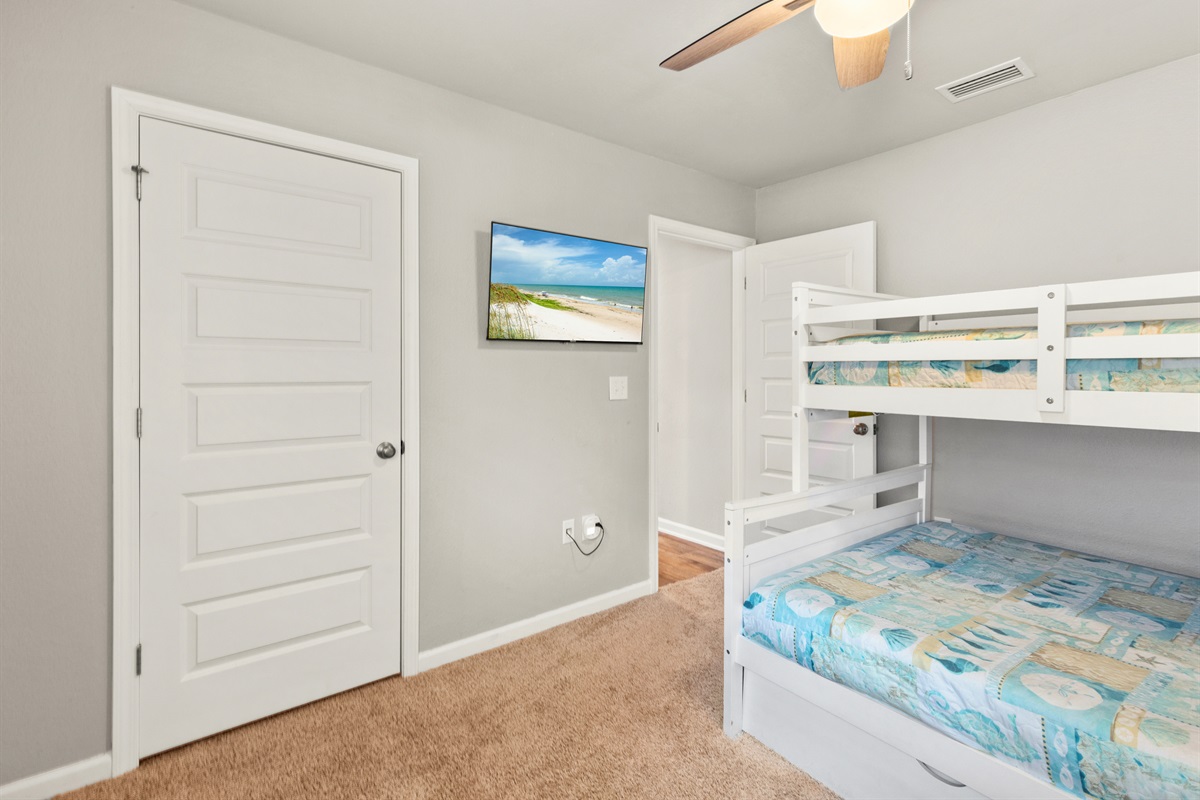 Bunk room with TV and closet, making it a great retreat for the younger crew.