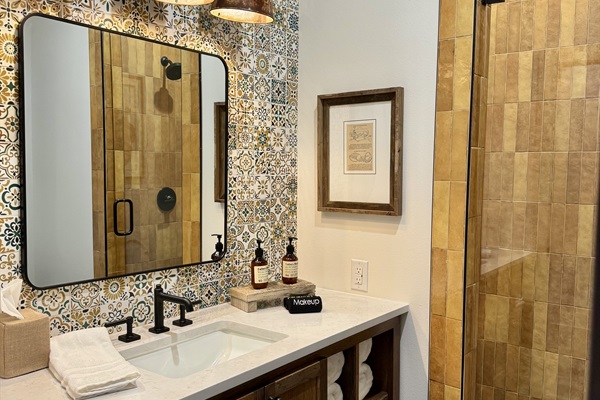 Private en-suite bathroom at the Lazy Spur Suite &mdash; designer vanity, Hill Country mosaic tile, and modern Western finishes at Gaines Ranch on the Square.