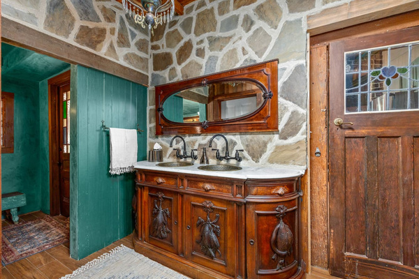 Even practical spaces deserve a little theater. In the Powder Room Annex, a 1920s dresser was transformed into a shared double vanity with handmade copper sinks. The stone walls add sound insulation, texture and a wonderful sense of permanence.
