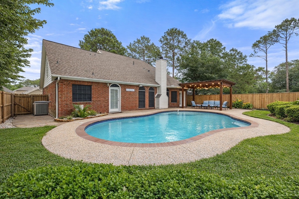 Spacious outdoor living area with a refreshing pool, covered patio lounge, and inviting atmosphere for the ultimate getaway.