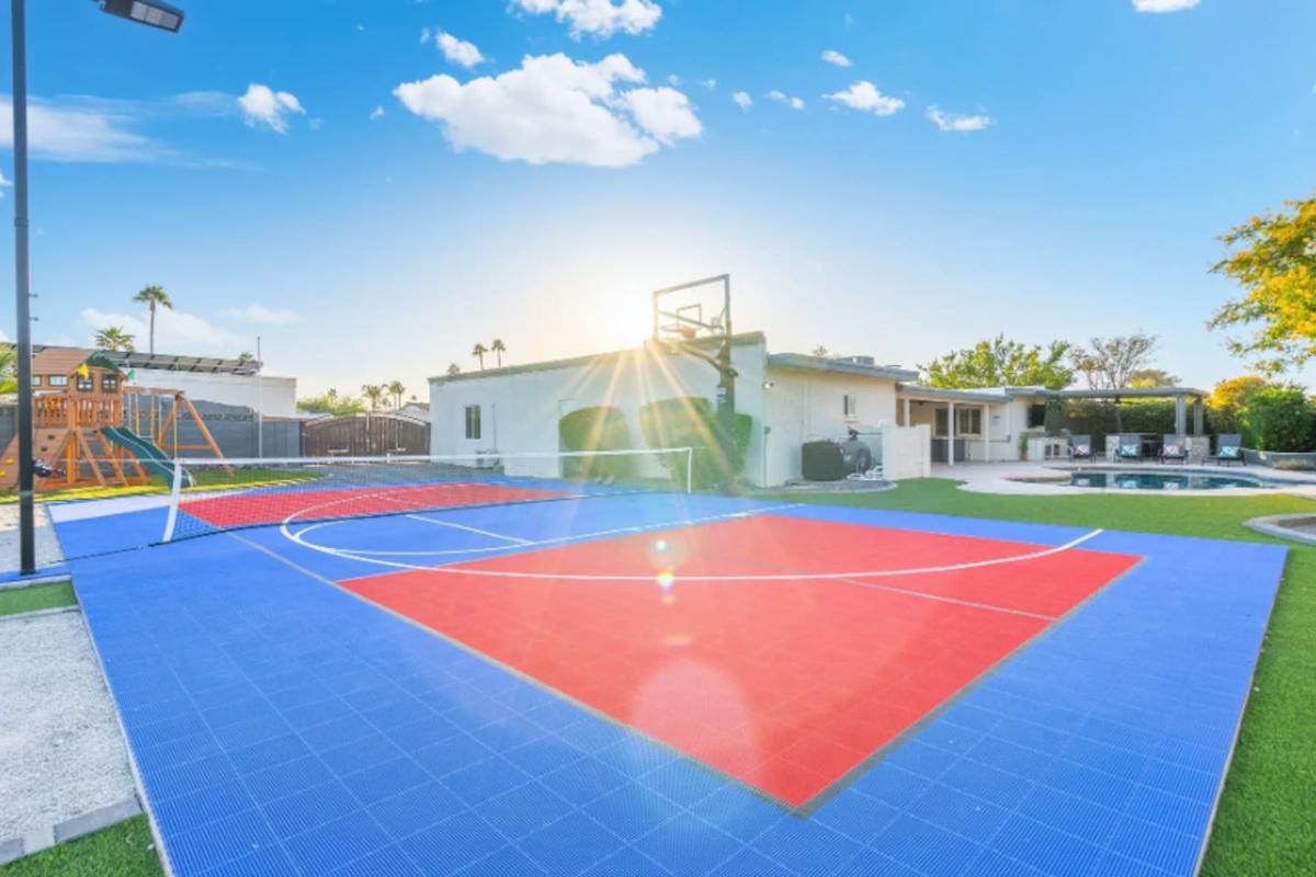 Sunlight streams across the court in this golden-hour shot, framed by the home and mountains beyond.

