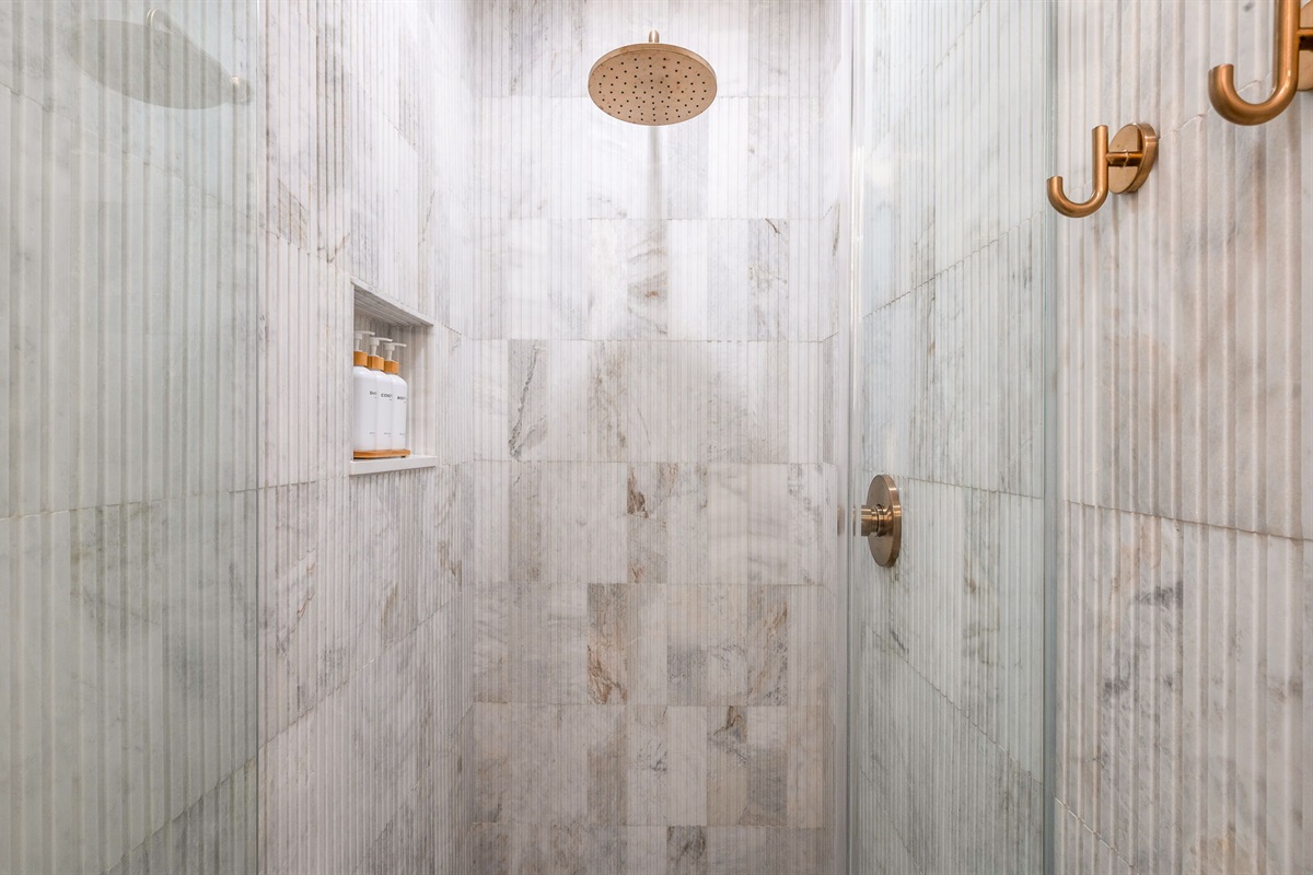 Full Bathroom #3: Discreetly located off the dining room, this newly built guest bathroom showcases floor-to-ceiling fluted marble, a spa-inspired shower, floating vanity, and an elegant make-up bar for a true resort feel.