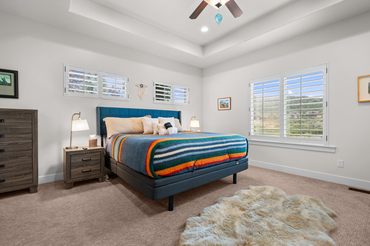 Luxurious primary suite featuring a king bed, vaulted ceilings, and a peaceful retreat atmosphere.
