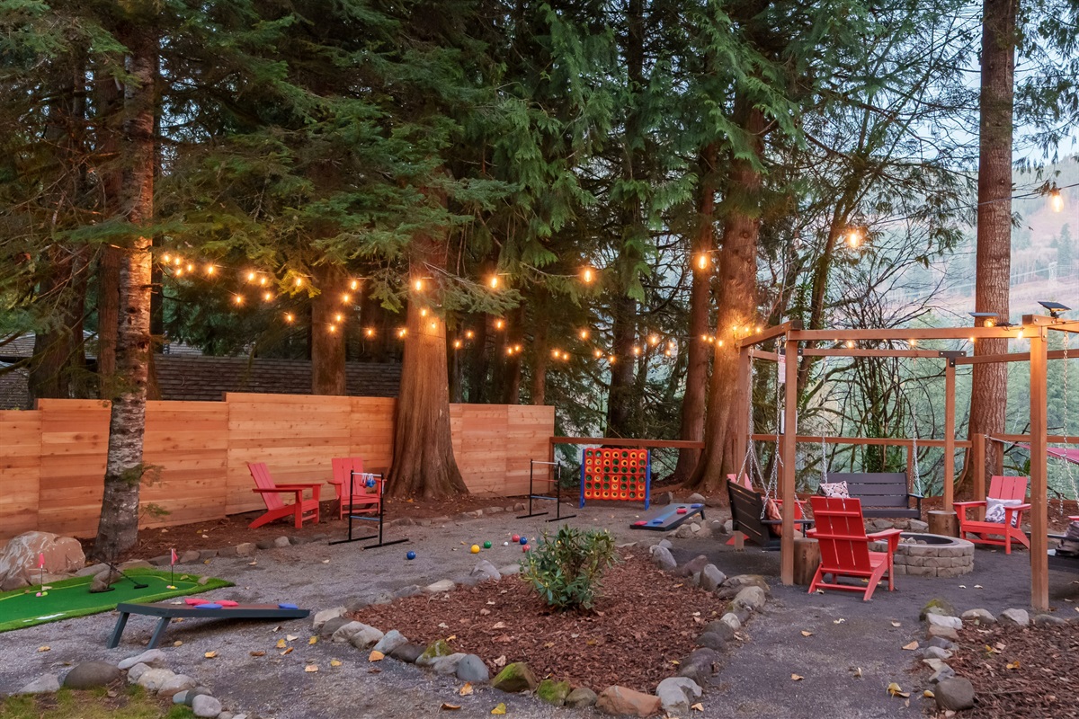 A backyard made for fun—putt-putt golf, cornhole, giant Connect 4, ladder ball, bocce ball, and hammock lounging, all centered around a glowing fire pit under string lights. Perfect for families and groups.