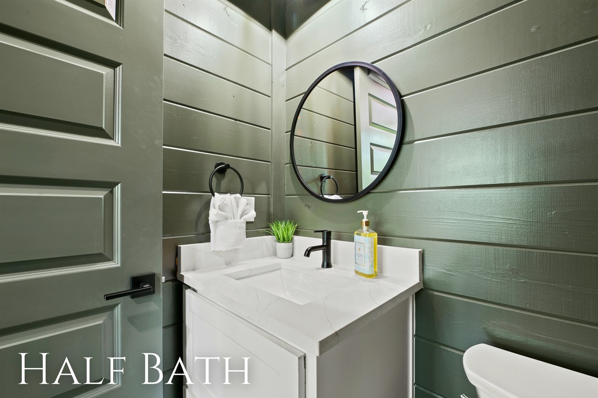 Stylish half bath pairs green walls with sleek, modern fixtures, offering a fresh and streamlined look.