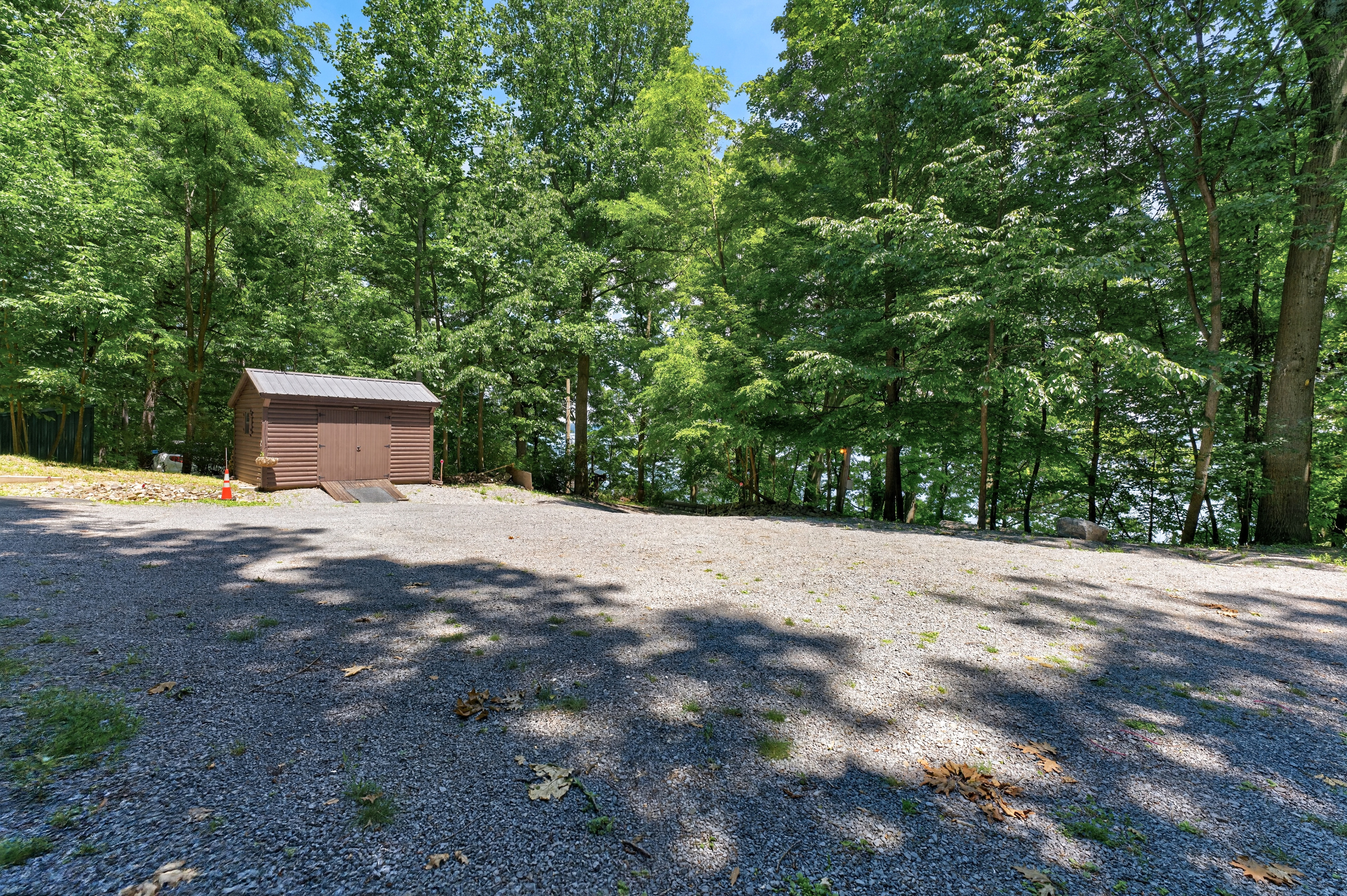 Tree-lined gravel area near an outbuilding