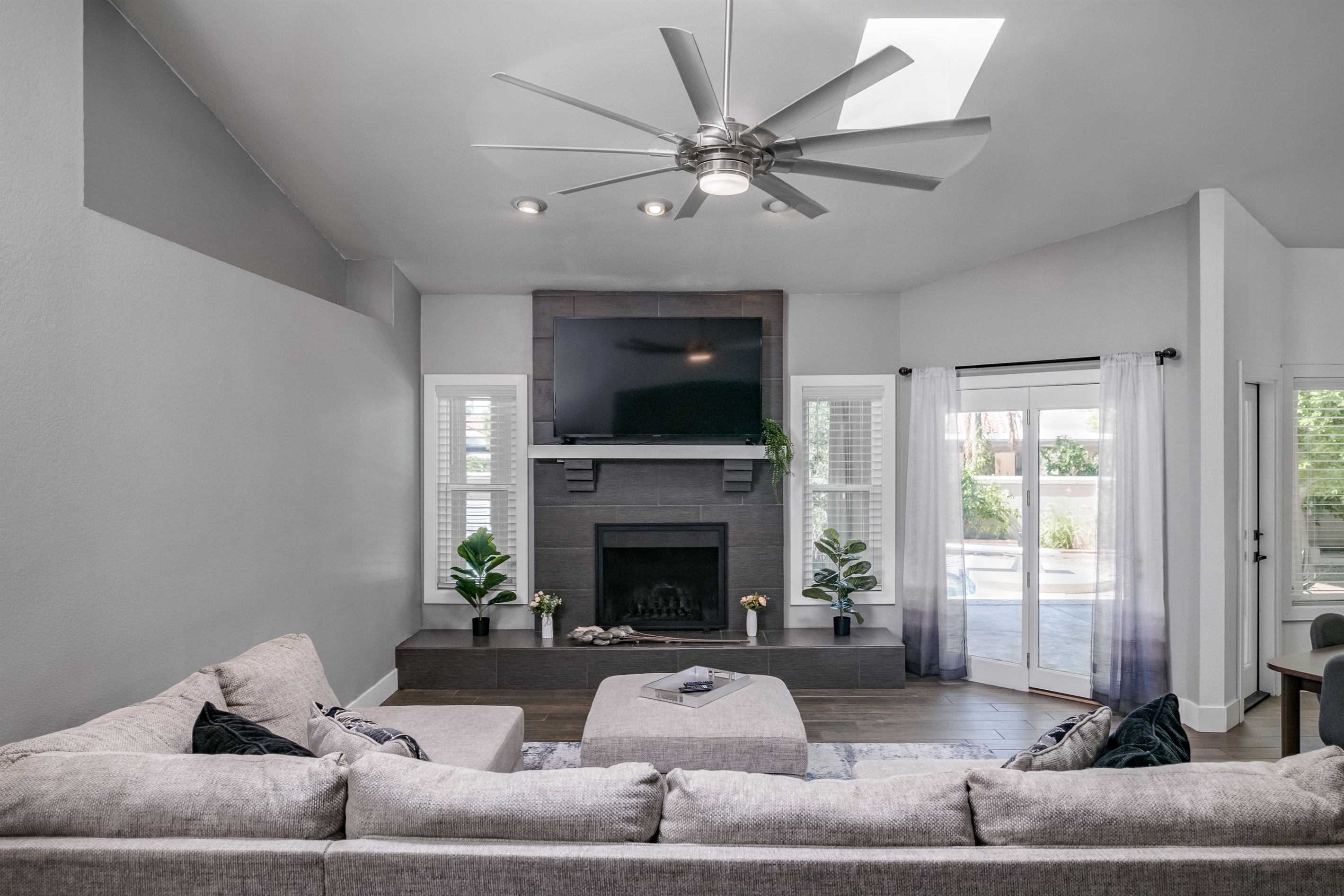 Spacious and sunlit, this living room features soaring ceilings, a cozy fireplace, and plenty of room for movie nights or game-day gatherings.