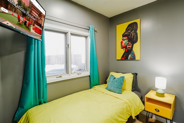 modern space highlighted by a vibrant yellow painting against a cool gray wall, complemented by a chic lamp and a TV for a blend of style and entertainment.