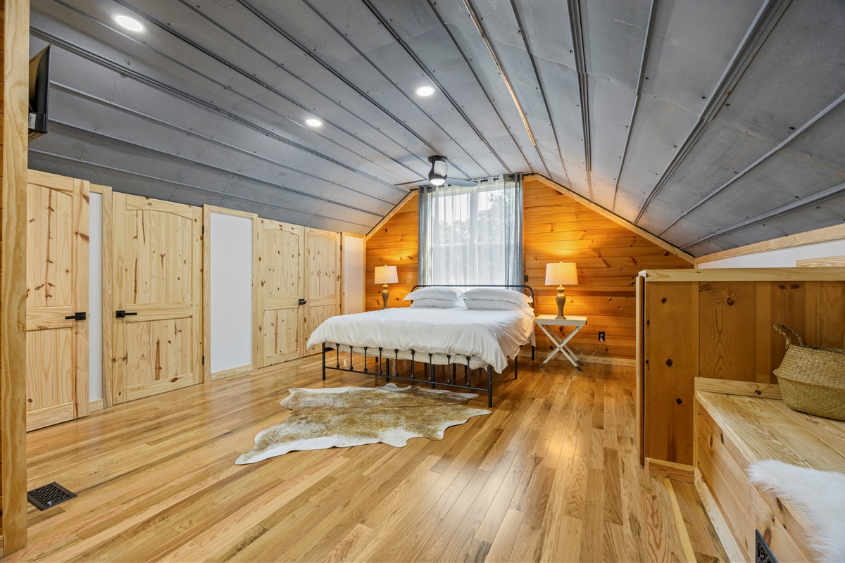 Spacious primary bedroom with king bed, vaulted ceilings, and warm wood accents.
