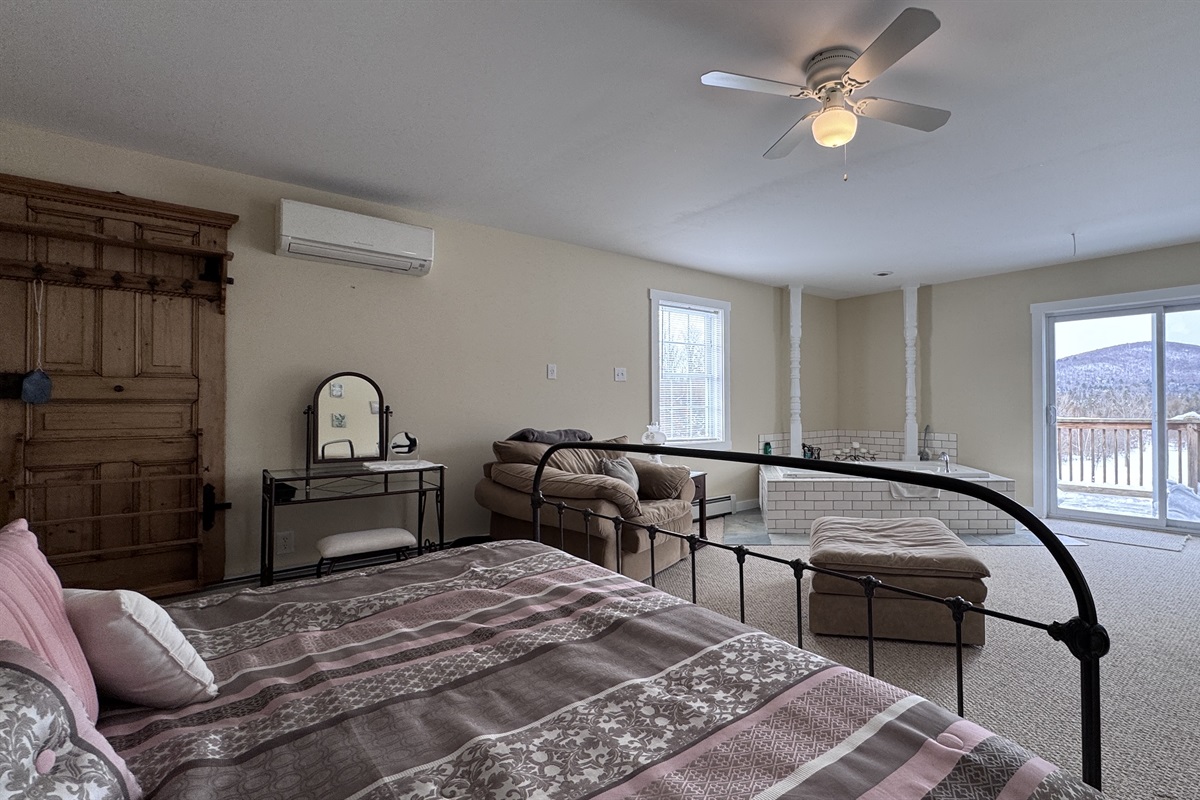 Primary bedroom with private wet bar, large stand-alone soaking tub, and access to private balcony 